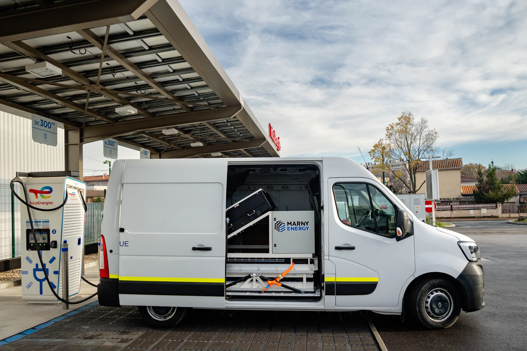 Marny mobile energy unit in a white Renault Master van with the side door open, charging at a TotalEnergies DC fast-charging station